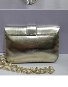 Dettaglio della borsa da sera dorata in similpelle con catena di perle e patta a busta