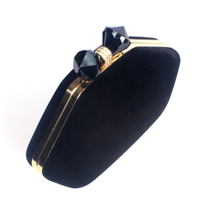 Detailed close-up of a black velvet evening clutch with a crystal bow-shaped clasp
