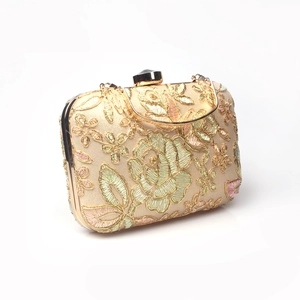 Detailed close-up of floral embroidery and gemstone clasp on gold evening clutch bag