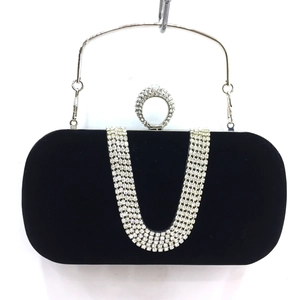 Detail of black velvet evening clutch featuring U-shaped rhinestone bands and ring buckle