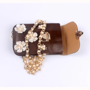 Detail der braunen Tasche mit 3D-Blumen und goldener Perlenkette im Retro-Stil