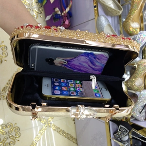 Detail view of the champagne and red rhinestone trim on a gold evening clutch bag