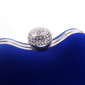 Macro shot of silver frame and crystal ball clasp on a navy blue velvet evening clutch bag