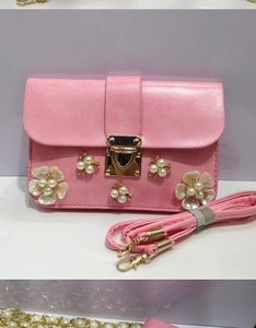 Dettaglio della borsa rosa in ecopelle con fiori di perle e chiusura a cuore