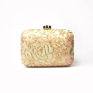 Detailed close-up of champagne floral embroidery and gemstone clasp on dinner clutch bag