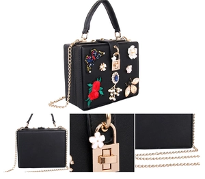 Detail of black evening bag with butterfly embroidery, 3D floral accents and gold chain