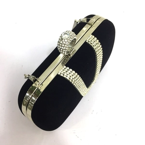 Detail of a black velvet evening clutch bag with sparkling rhinestone ring closure
