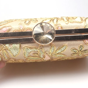 Close-up of floral embroidery detail and crystal clasp on luxury evening clutch bag