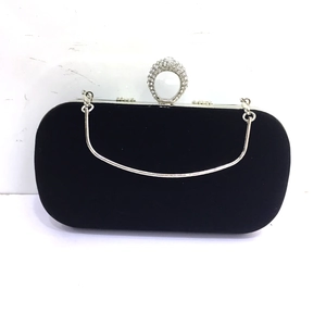 Detail of black velvet clutch with crystal ring handle and silver metal accents