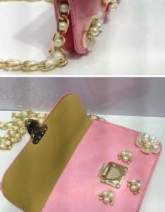Dettaglio borsa floreale rosa con perle, catena dorata e chiusura magnetica