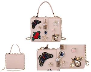 Detail of pink evening bag featuring butterfly embroidery, rose patches, and pearl beads