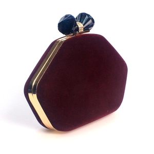 Detail view of burgundy velvet hexagon clutch with gold frame and crystal clasp