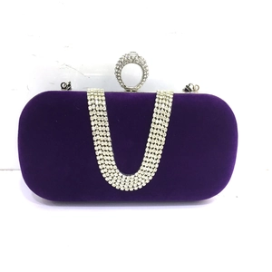 Detailed view of a purple velvet evening bag with U-shaped rhinestone chains and ring clasp