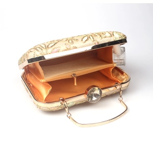 Macro view of floral embroidery evening bag showing orange satin lining and zipper pocket