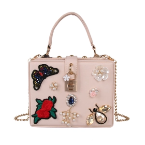 Detail of butterfly and rose embroidery with rhinestone bee and pearls on pink clutch bag