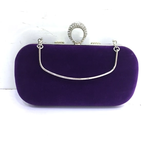 Macro detail of purple velvet evening clutch featuring diamond-studded ring closure