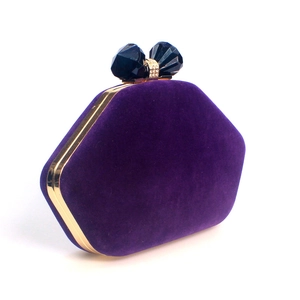 Detail view of purple velvet evening clutch with golden frame and blue crystal bow clasp
