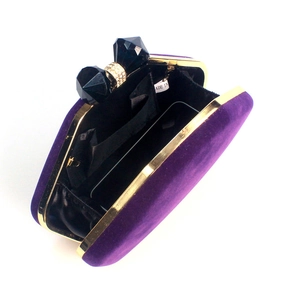 Detail view of purple velvet clutch with golden frame and rhinestone bow clasp