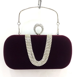 Detail of velvet evening clutch featuring V-shaped crystal chains and ring clasp