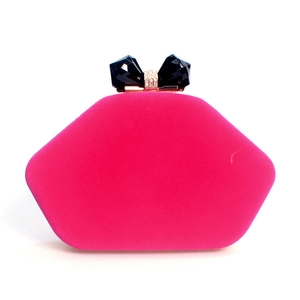 Detailed view of fuchsia velvet evening bag featuring a black crystal bow clasp and gold trim