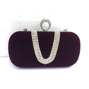 Detail of dark wine red velvet clutch with U-shaped rhinestone chain and ring closure