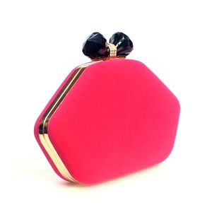 Macro detail of fuchsia velvet clutch featuring gold metal frame and black bow crystal clasp