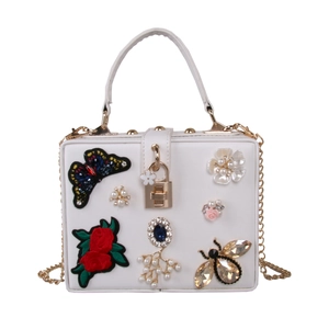 Close-up of white evening bag with butterfly embroidery and jewel embellishments