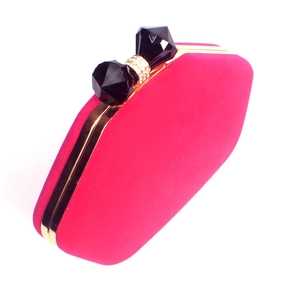 Detail of rose red velvet evening bag with a crystal bow clasp and gold metal frame