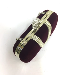 Macro detail of burgundy velvet clutch with crystal rhinestones and diamond ring clasp