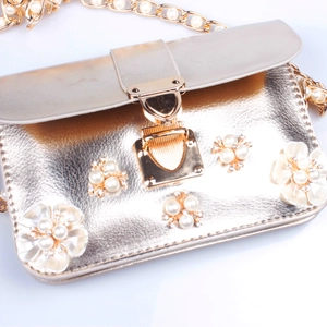 Dettaglio borsa a tracolla dorata con fiori di perle e decorazioni in strass brillanti