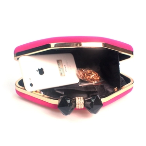 Macro view of velvet evening bag interior with gold chain and black crystal bow clasp