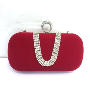 Macro shot of red velvet clutch bag with U-shaped rhinestone chain and diamond ring clasp