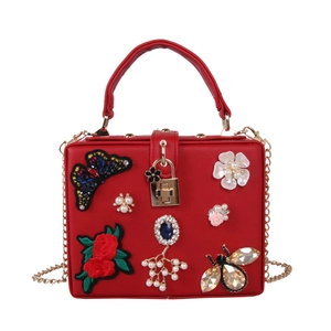 Close-up of red evening bag with butterfly embroidery, pearls and gemstone bee details