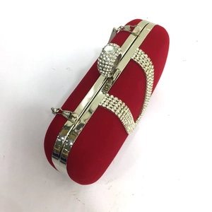 Macro detail of red velvet clutch bag with U-shape crystal clasp and silver metal frame