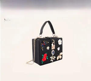 Detail of black box evening bag featuring embroidered butterflies and 3D floral accents