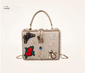 Detail of champagne gold evening bag with butterfly embroidery and pearl floral rhinestones