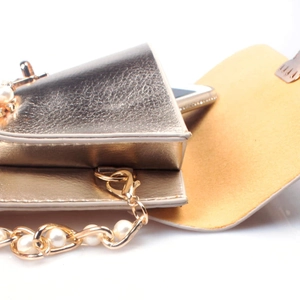 Dettaglio mini borsa oro champagne in pelle litchi con catena di perle e spazio per telefono