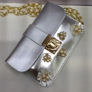 Dettaglio borsa da sera argento con fiori di perle e tracolla a catena dorata lucida