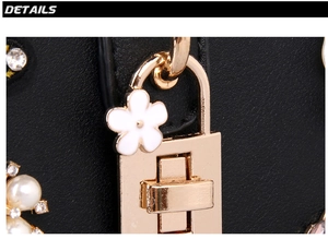 Detail of golden twist lock with enamel flower and pearls on black embroidered evening bag