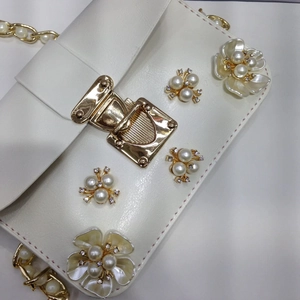 Dettaglio borsa a tracolla in pelle PU bianca con fiore di perle e catena in metallo oro