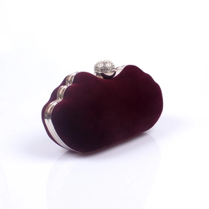 Macro detail of wine red velvet clutch bag featuring a silver crystal spherical clasp