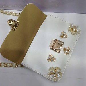 Dettaglio della borsa a tracolla floreale con perle, strass e catena metallica dorata