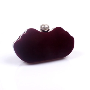 Close-up of luxury wine red velvet clutch bag with a sparkling rhinestone spherical clasp