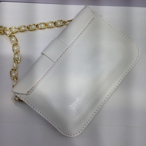 Dettaglio della borsa a tracolla in pelle PU bianca con cuciture rosa e catena di perle