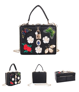 Detailed view of butterfly embroidery and pearl floral accents on black evening clutch bag