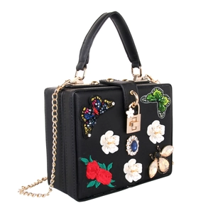 Detailed view of black evening bag with butterfly embroidery, pearls and blue jewels