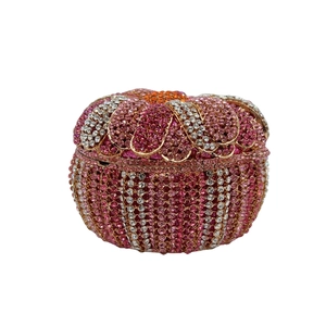 Makroaufnahme einer Luxus-Clutch mit rosa Strassverlauf und goldenem Wellenrand