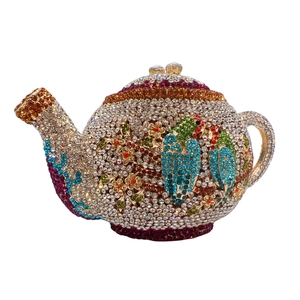 Macro shot of teapot-shaped evening bag with colorful crystals and floral bird patterns