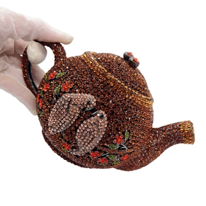 Luxury teapot-shaped clutch bag with deep orange crystals and bird floral motifs