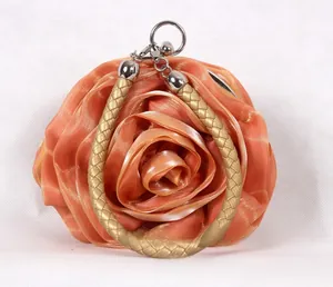 Détail des pétales de rose en soie orange et de la poignée dorée du sac de soirée élégant